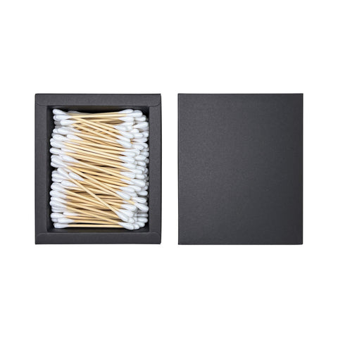 Black box with cotton swabs and wooden sticks on a white background