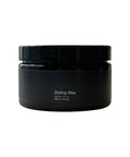 Black jar of styling wax on a white background