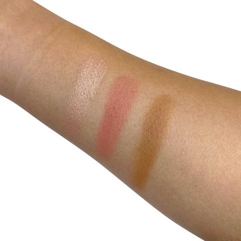 Three makeup swatches on a person's arm with different shades of pink and brown.