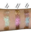 Three glittery makeup swatches on a person's arm labeled SHM07 Rosy, SHM06 Euphoria, and SHM05 Goldie.