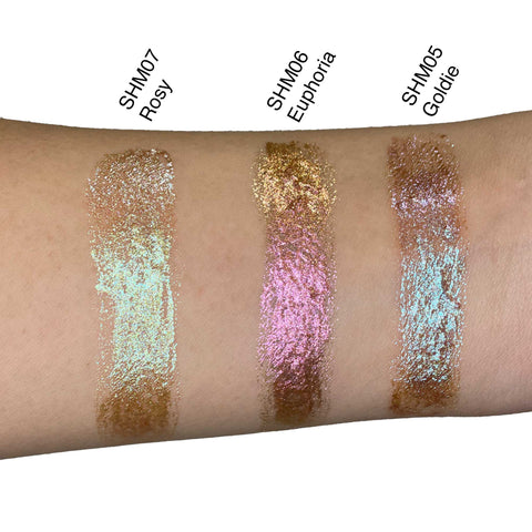 Three glittery makeup swatches on a person's arm labeled SHM07 Rosy, SHM06 Euphoria, and SHM05 Goldie.