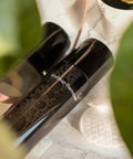 Makeup remover on a marble surface with blurred green leaves in the foreground