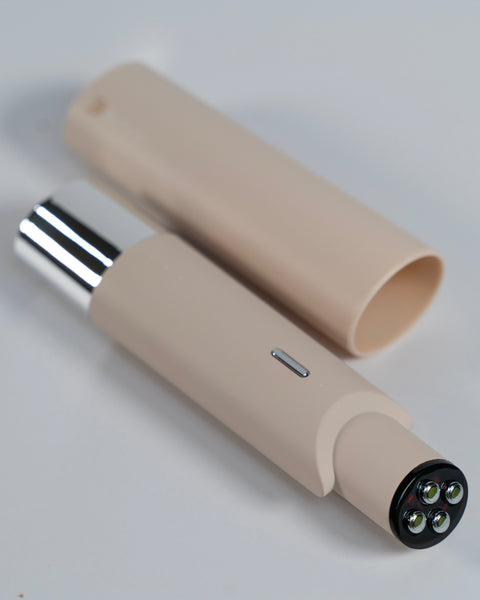 Beige handheld device with a metallic nozzle on a light gray background