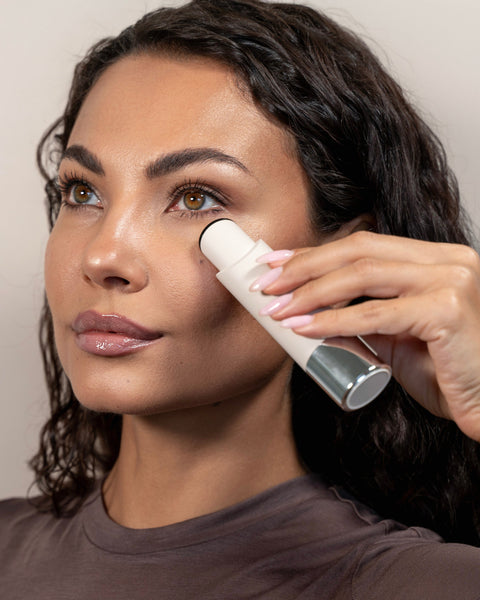 Woman applying a skincare product to her face using a applicator.