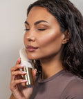 Woman using a skincare device on her face against a neutral background
