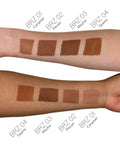 Swatches of brown makeup shades on a person's arm with color names below.