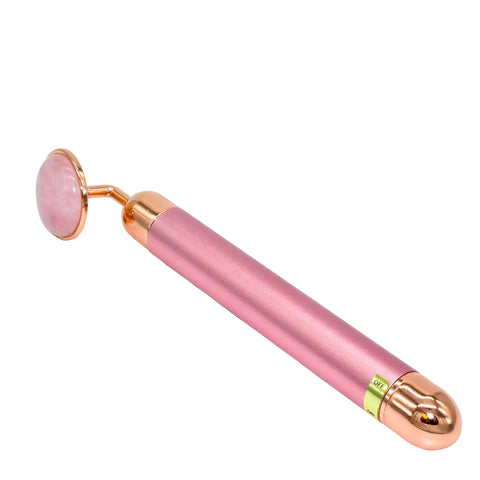 Pink and rose gold facial roller on a light gray background