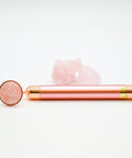 Rose gold facial roller with pink stone on a white background