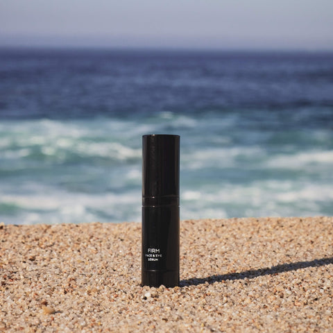 Black cylindrical product on a sandy beach with ocean in the background