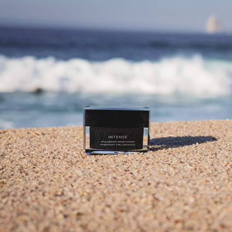 Cosmetic container labeled 'Intense' on a beach with ocean in the background