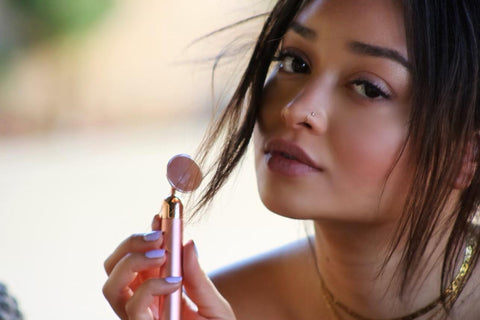 Woman holding a pink and gold makeup tool outdoors