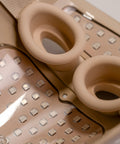 Close-up of a beige kitchen grater with two circular attachments on a white background.
