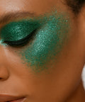 Close-up of a person with green glittery eye makeup.