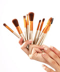 Hand holding a set of makeup brushes against a white background