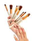 Hand holding a set of makeup brushes against a white background