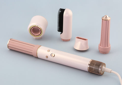 Pink and gold hair styling tool with detachable parts on a light gray background