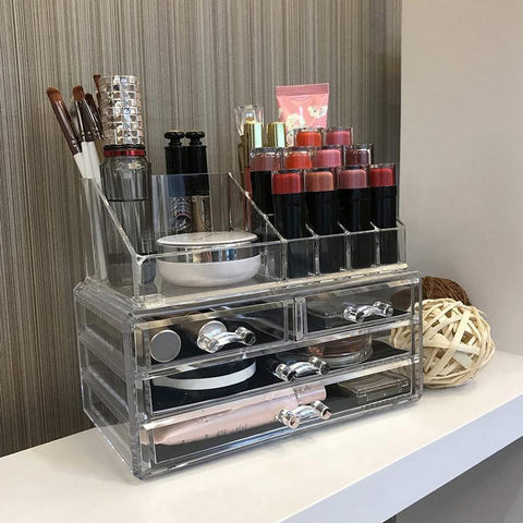Clear acrylic cosmetic organizer with makeup items on a desk.