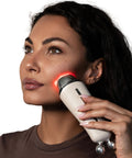Woman using a skincare device on her face with a neutral background