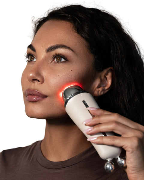 Woman using a skincare device on her face with a neutral background