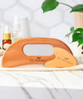 Wooden roller with J&L Naturals branding on a white surface with plants in the background